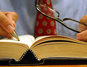 Man checking a law book with help of pen