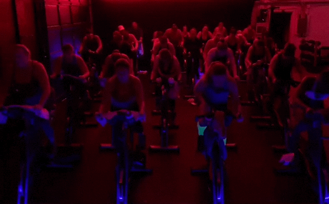 A group of people are riding exercise bikes in a gym.